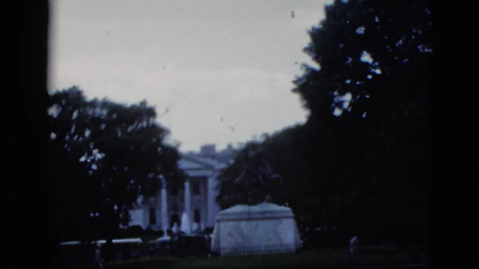 Wide 8mm shot of the White House north facade and equestrian statue from a visitor vantage, Washington DC, c.1952; a small figure is visible near the pedestal base.