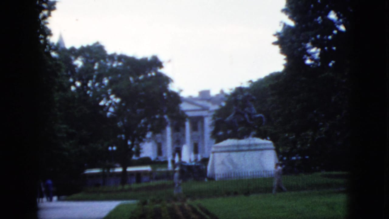 Exterior view of a white columned building and equestrian statue, likely in the Washington DC area, circa 1952; 8mm film with visible grain and cool color cast.