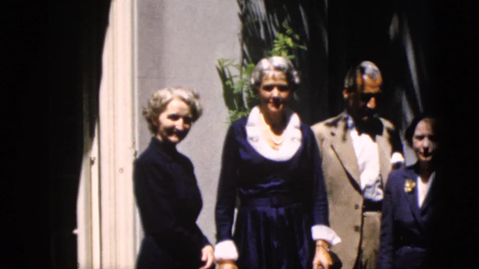 Four adults in formal mid-century clothing pose outside a building entrance in 1952 Washington, DC home-movie footage.