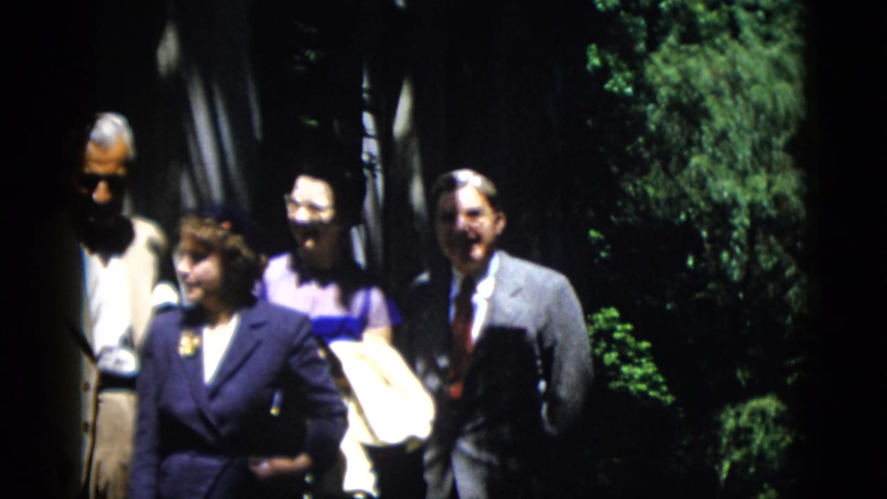 1952 Washington DC home-movie frame showing adults in suits and dresses posing outdoors in sun and shade.