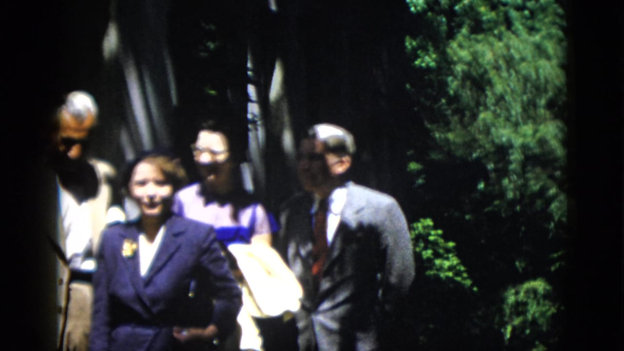 A small group of adults smiles toward the camera in a shaded outdoor setting.
