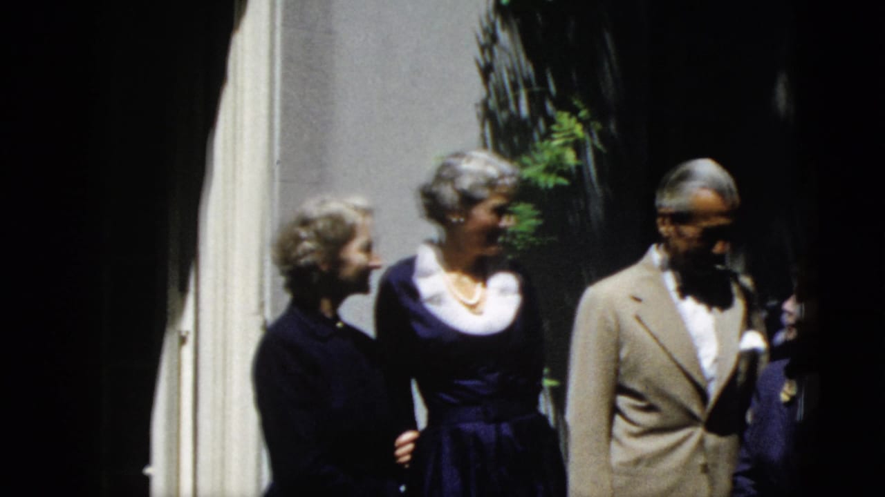 Six adults appear to pose outdoors in Washington, DC in 1952, wearing suits and dark dresses near a shaded building wall.