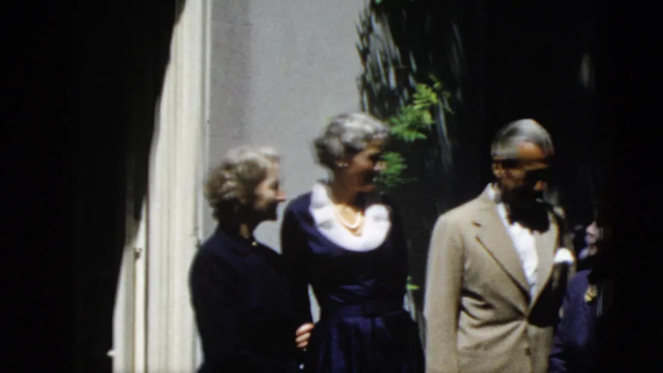 Six adults appear to pose outdoors in Washington, DC in 1952, wearing suits and dark dresses near a shaded building wall.