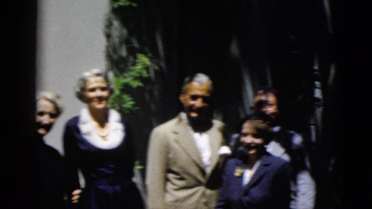The group poses in bright daylight, with several faces turned toward the camera and one woman partly obscured in shadow.