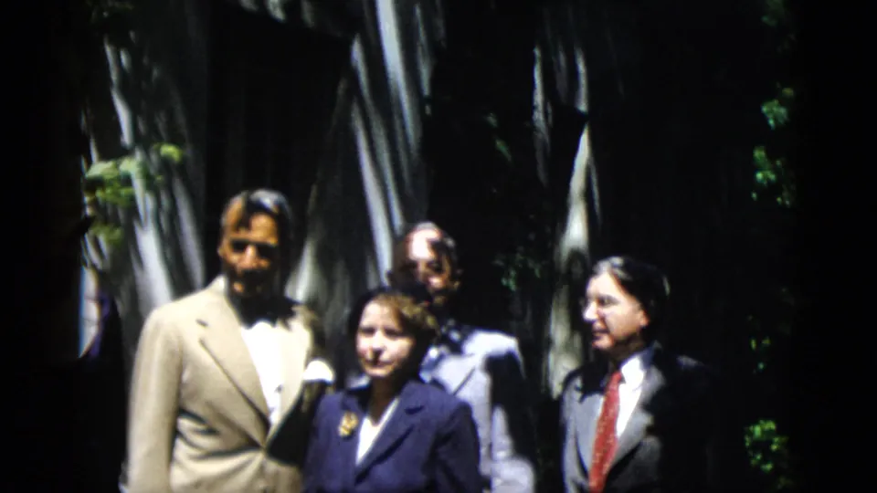 A slightly reframed 1952 Washington, DC home-movie view shows the formal group standing beneath tall trees.