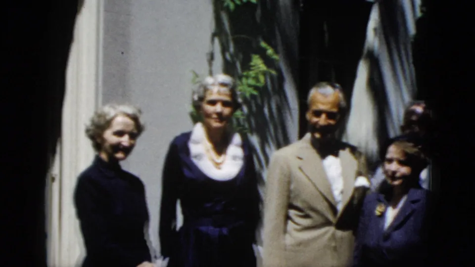 Home-movie frame of formally dressed relatives posing outside a Washington, DC house in 1952.