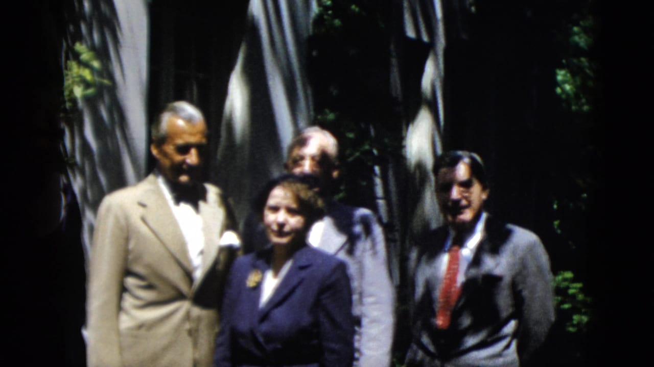 Formally dressed adults stand together outdoors under trees.