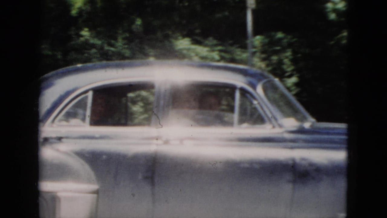 Vintage sedan passing through a shaded wooded area.