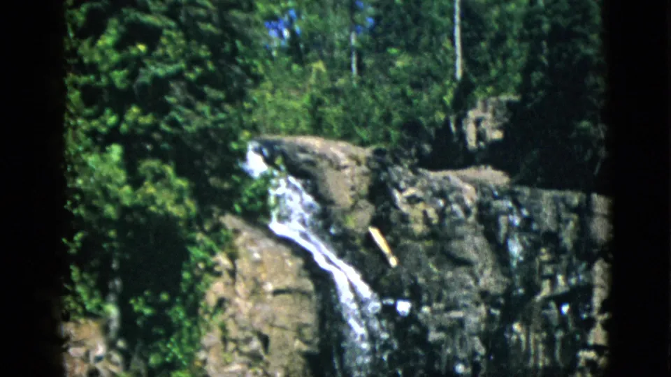A small waterfall pours over dark rock ledges in the Quebec woods, filmed on 8mm during a 1952 vacation.