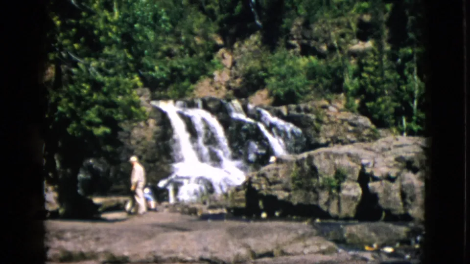 Wide 8mm view of a two-tiered waterfall in Quebec, Canada, circa 1952; two small figures near the rocky foreground at lower left.