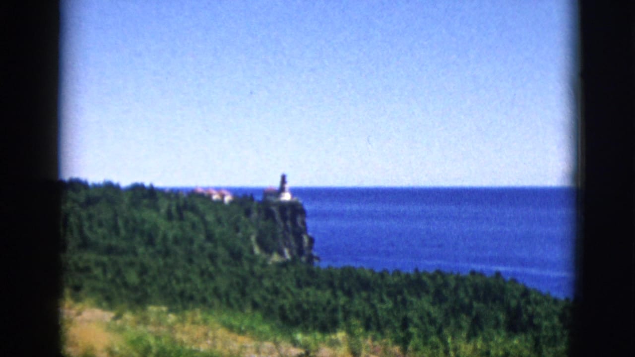 8mm color footage attributed to Quebec, Canada, c. 1952, showing a lighthouse on a forested rocky headland above an expansive body of water.