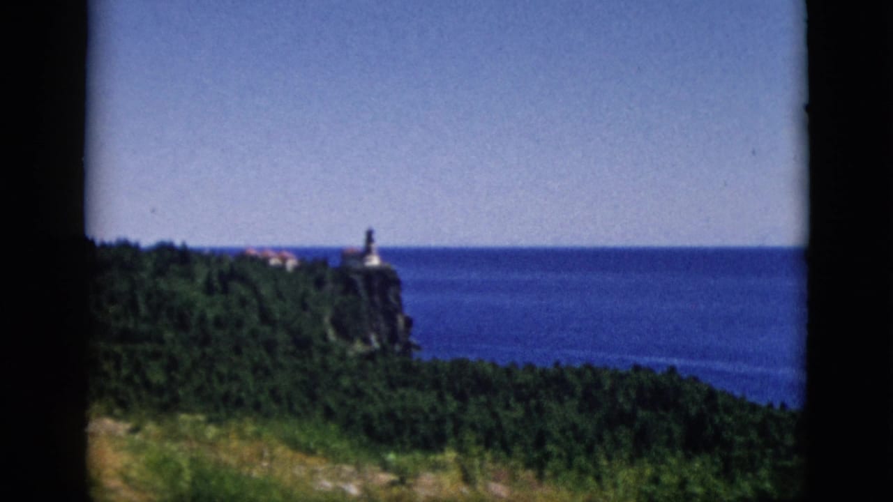 8mm pan continuing across lighthouse on forested cliff above large water body, c. 1952, attributed to Quebec, Canada.
