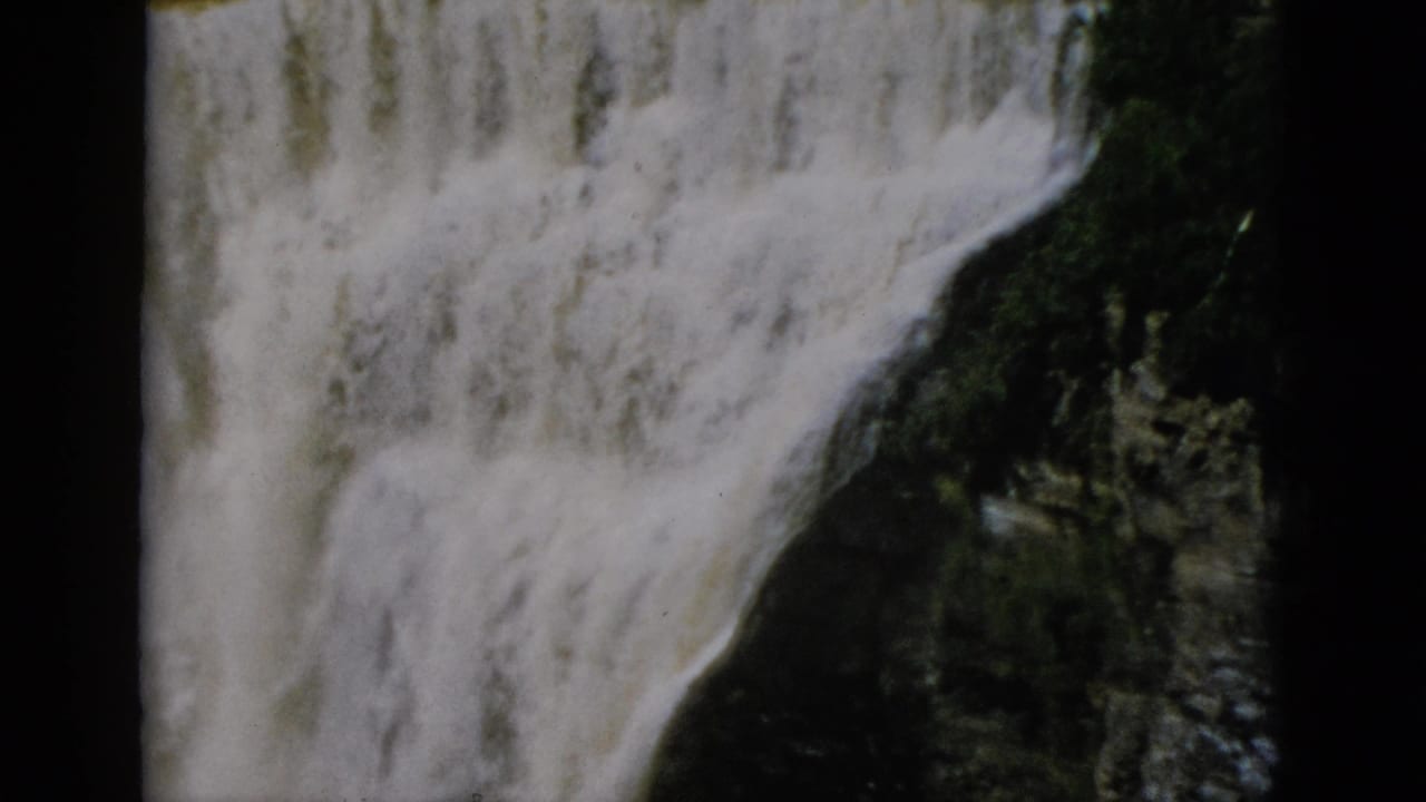 Large waterfall cascading down dark rock face, 8mm film, circa 1952.
