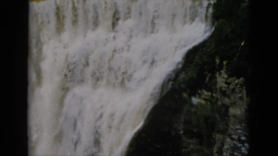 White-water falls cascade over dark layered rock in Quebec, Canada, captured on 8mm film circa 1952.