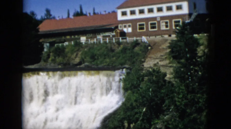 Powerful waterfall cascade and rocky gorge walls with hotel building above, Quebec Canada circa 1952, 8mm home movie frame at end of pan.
