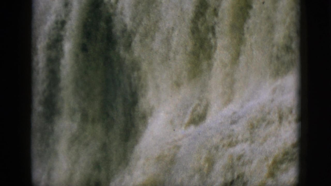 Tight shot of a heavily flowing waterfall on 8mm home movie film, likely Quebec, Canada, circa 1952; frame filled with churning yellowish-white water