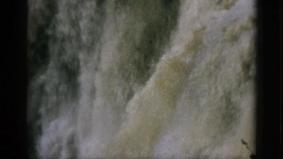 Close-up of a waterfall cascade on 8mm home movie film, circa 1952, water filling the frame with visible grain and warm color aging