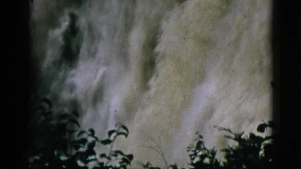 Lower portion of a powerful waterfall on 8mm home movie film, circa 1952 Quebec; dark green vegetation visible at the base of the falls