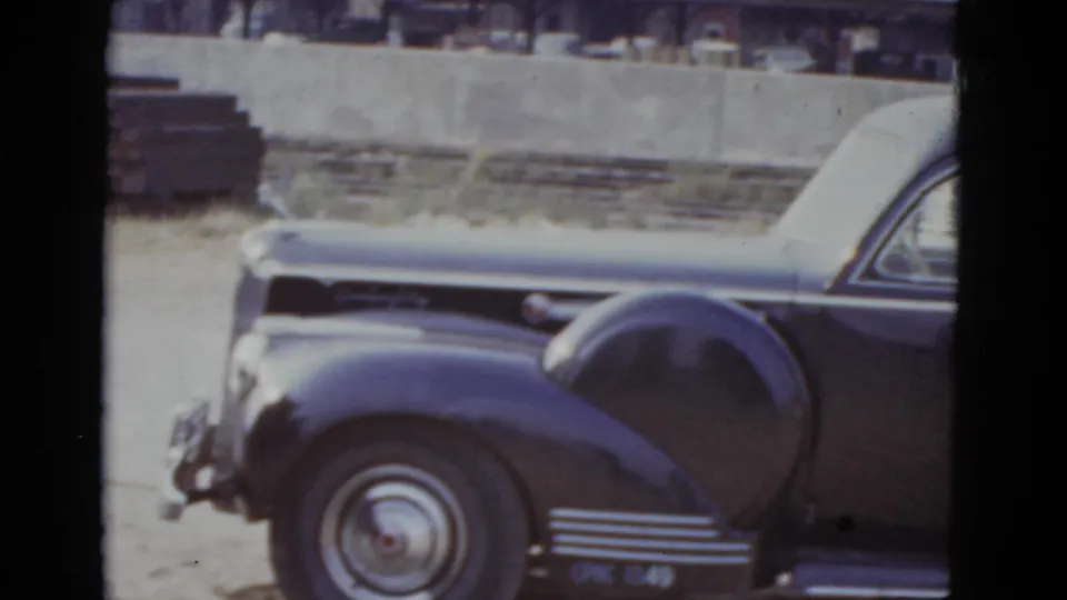 A dark rounded-fender American sedan, likely late 1930s or early 1940s manufacture, parked on a New Orleans street in 1952 8mm home-movie footage.