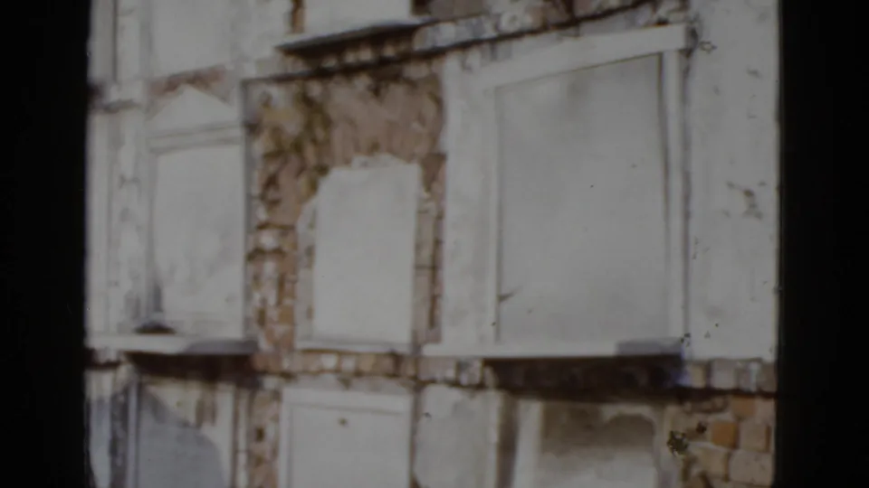 Lower facade of a deteriorating building with sealed flat-panel windows and ornate arched surrounds, New Orleans circa 1952, 8mm film.