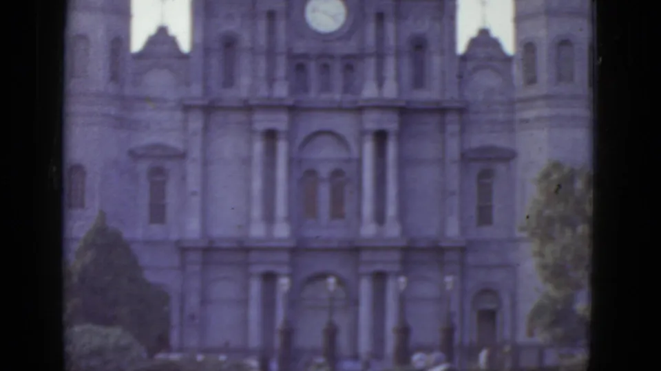 8mm home-movie view of a grand neoclassical facade with a central clock and tiered arched windows, likely a New Orleans landmark such as a cathedral or civic building, circa 1952.