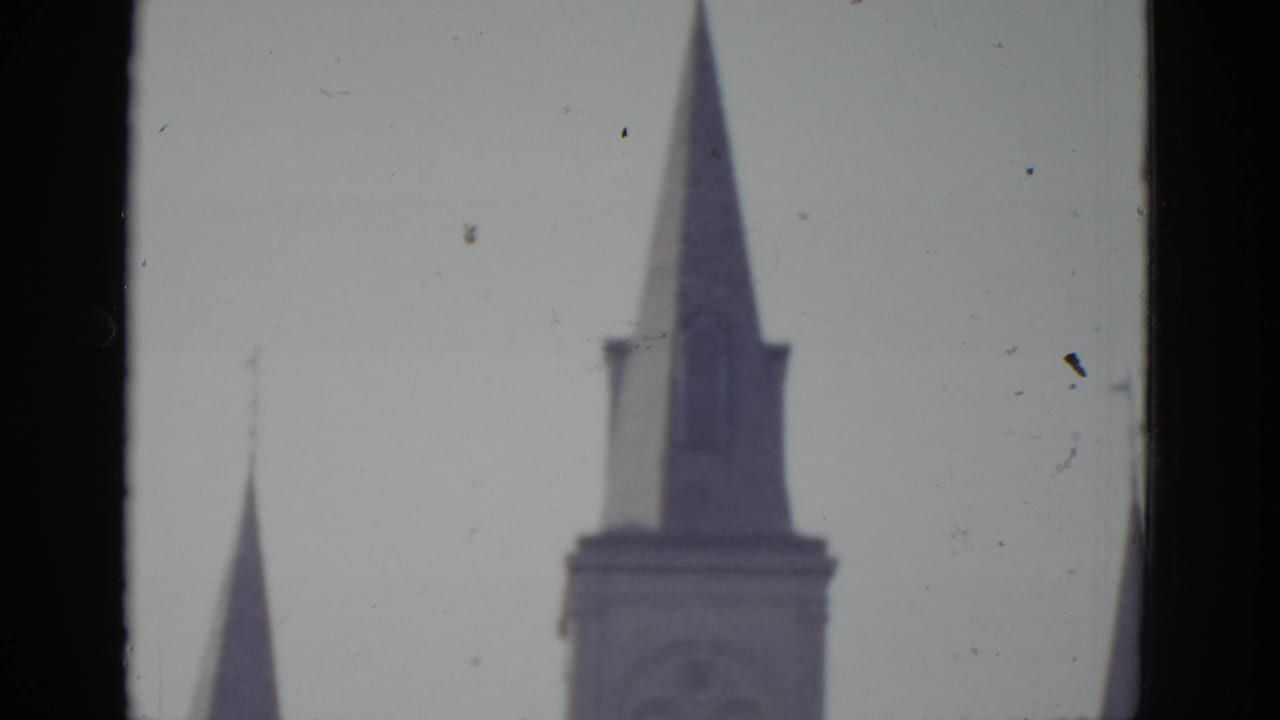 Two Gothic-style pointed church spires against an overcast sky, likely New Orleans, 8mm home movie c.1952.