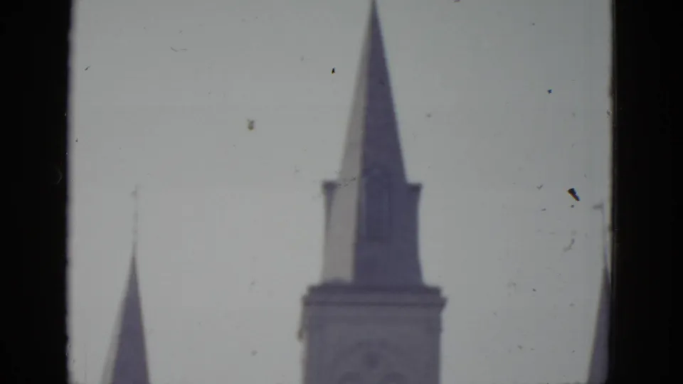 Two Gothic-style pointed church spires against an overcast sky, likely New Orleans, 8mm home movie c.1952.