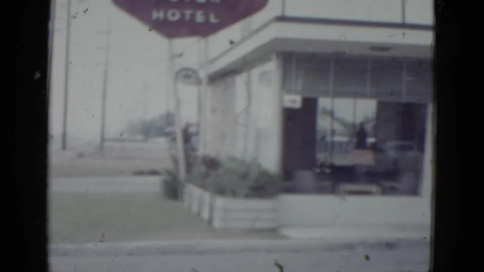 Close-up of a mid-century flat-roofed hotel with maroon HOTEL sign and glass-fronted lobby, New Orleans area, c.1952.