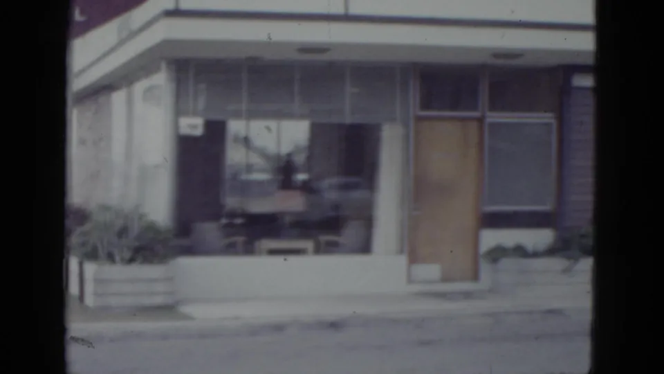 Mid-century flat-roofed hotel entrance with maroon HOTEL sign, glass facade, and circular emblem, New Orleans area, c.1952.