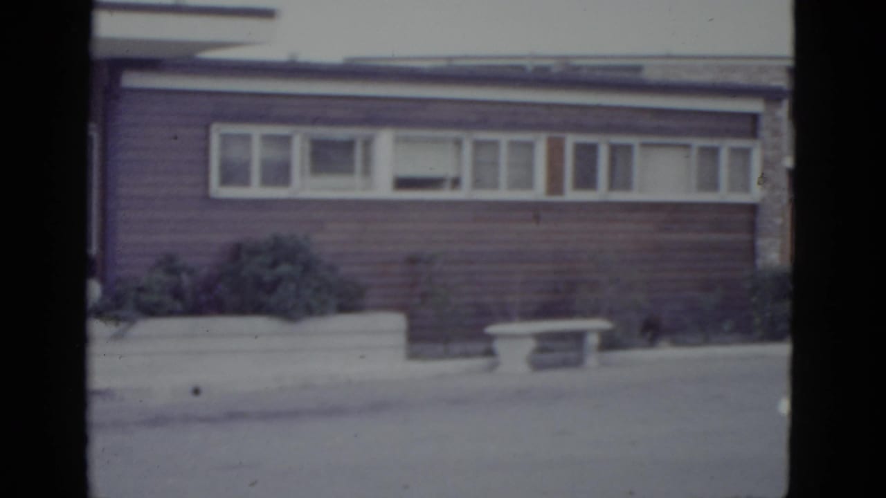 1950s ranch-style house with horizontal ribbon windows and concrete planter, filmed on 8mm circa 1952, possibly New Orleans area.