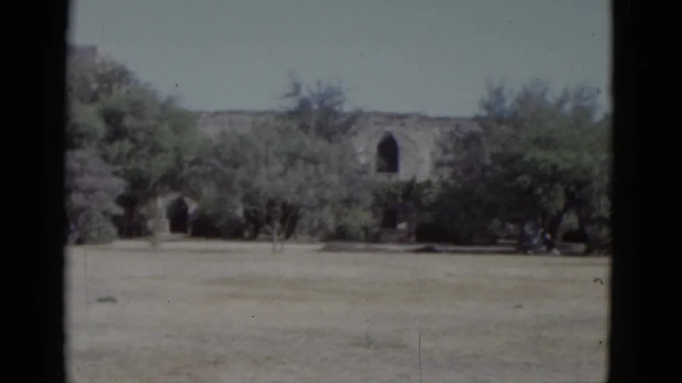 8mm home movie circa 1952 showing two arched openings in a Spanish colonial-style stone wall across dry ground, at an unconfirmed US historic site.