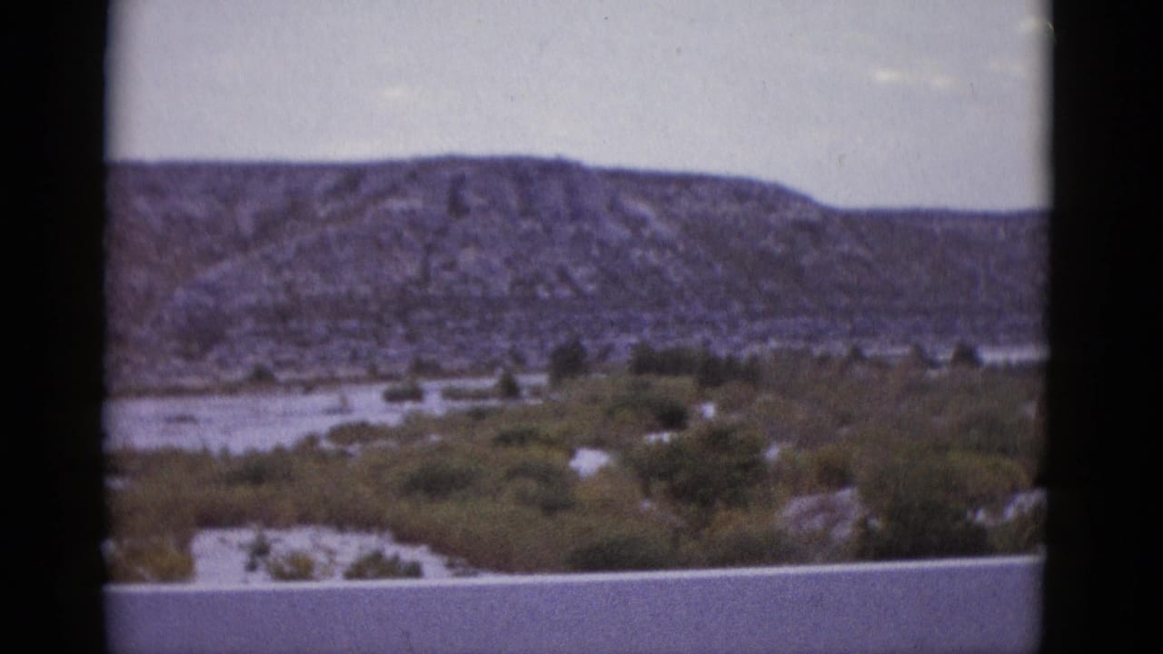 1952 Texas 8mm home movie showing the rocky mesa as the vehicle moves, desert vegetation and pale sky in view.