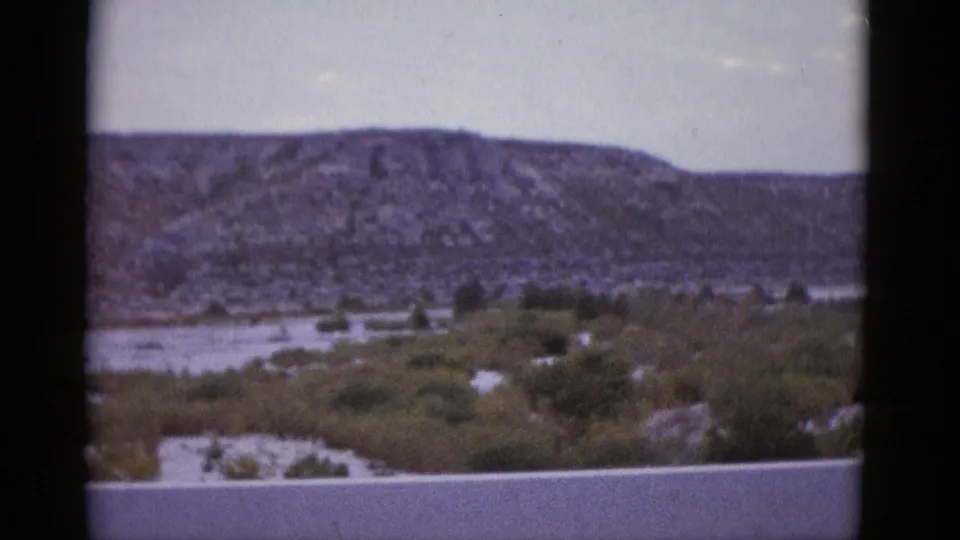 1952 Texas 8mm home movie showing the rocky mesa as the vehicle moves, desert vegetation and pale sky in view.