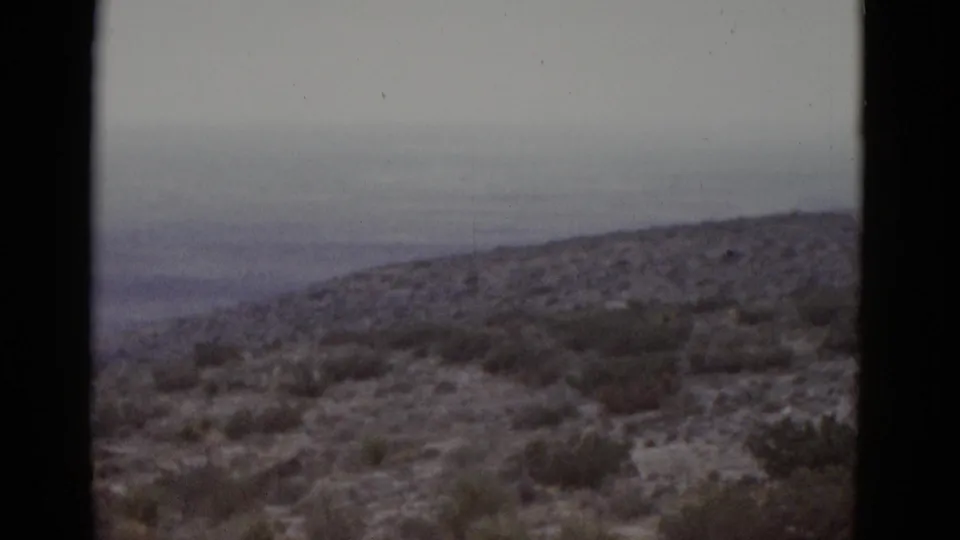 1952 Texas desert on 8mm — scrub-covered hills with a flat grey sky, camera panning across the landscape.