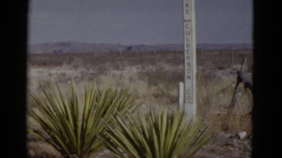 Roadside post reading 'CULBERSON CO' beside a foreground yucca plant, arid desert plain and mountain range visible beyond; American Southwest, circa 1952.