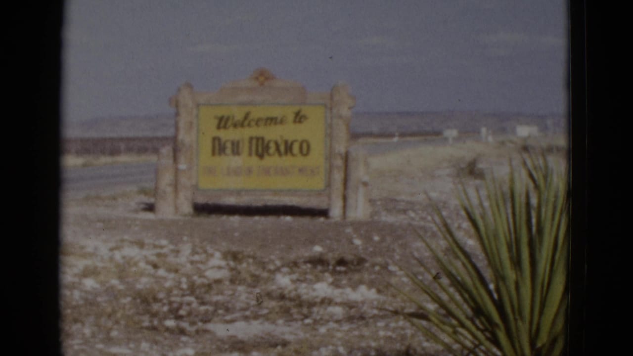 8mm home-movie frame of the New Mexico border welcome sign with yucca plant, c. 1952; composition nearly identical to the opening frame suggesting a held shot.