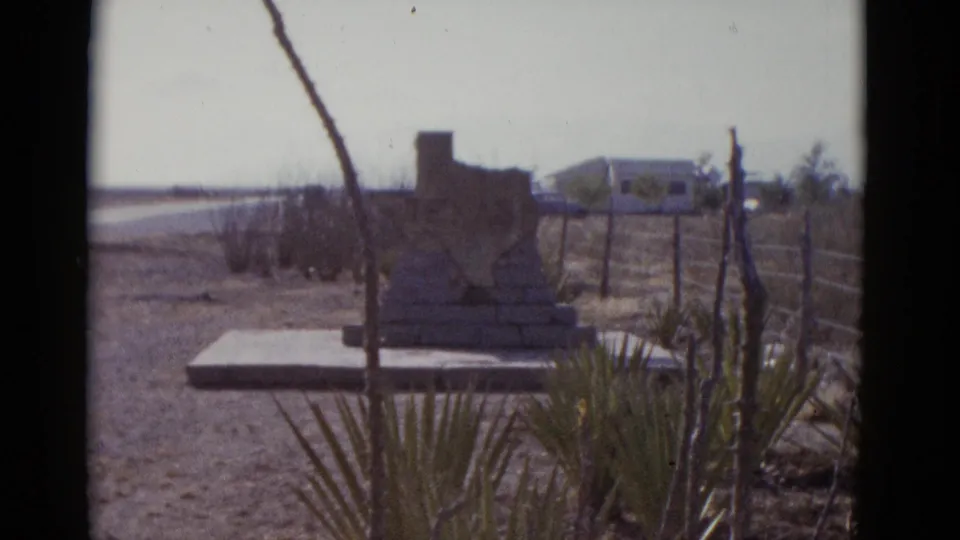 Final 8mm frame, circa 1952, of the Texas-shaped roadside monument; the background vehicle suggests the camera was operating from or near a moving car on the highway.