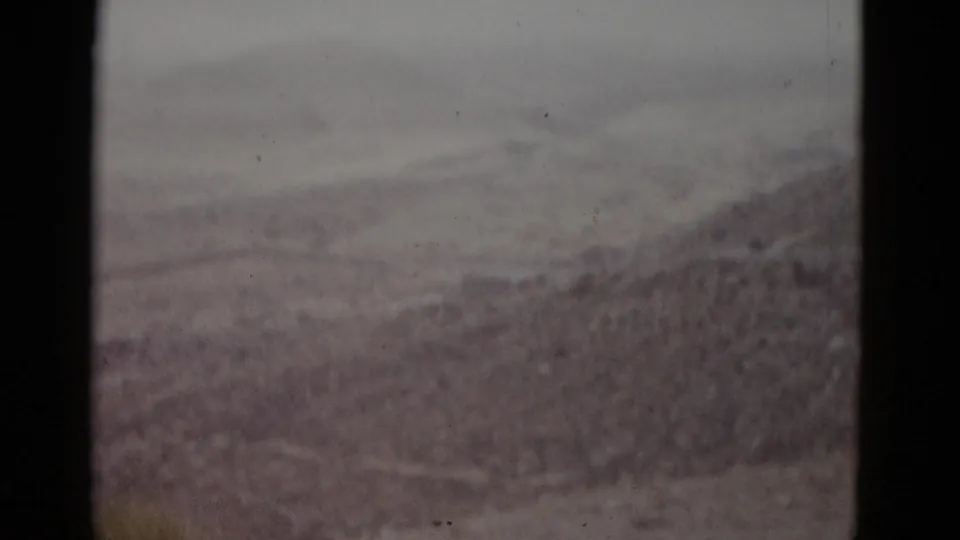 8mm home-movie frame, likely Utah, 1952 — rolling earth mounds and dry scrubland under an overcast sky.
