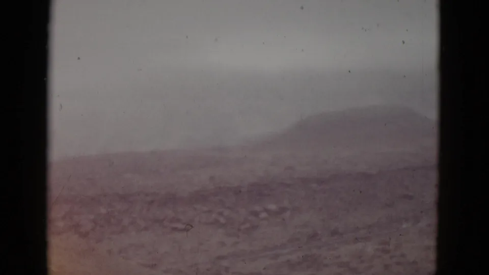 1950s 8mm home movie frame of the same Utah mountain vista with a subtle color shift toward warmer reddish-earth tones in the rocky foreground.