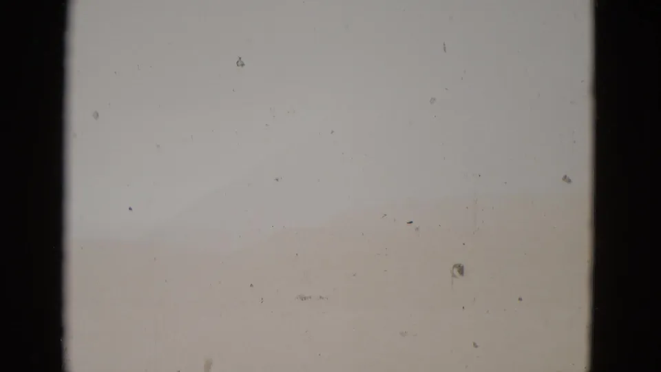 Near-blank 8mm frame showing severe overexposure or film fade at the reel's end; only dust specks and faint tonal variation are visible.
