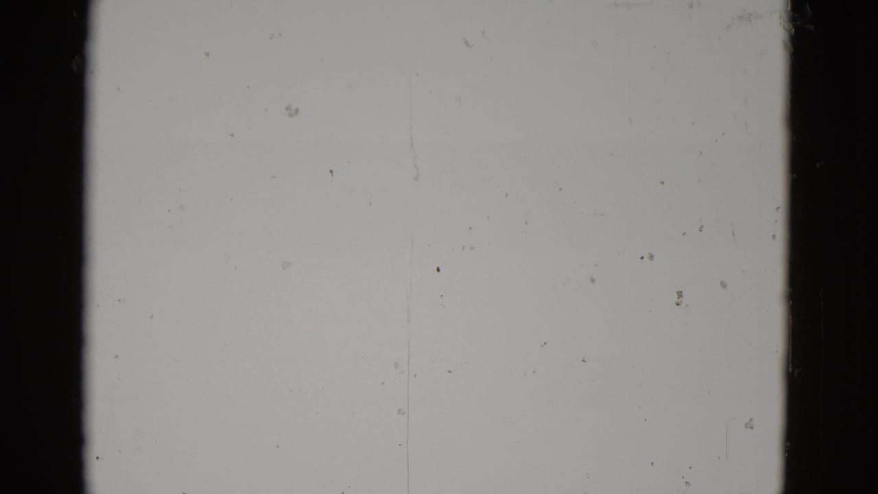 Severely overexposed 8mm frame from a 1952 Utah road trip; faint rocky terrain visible at the bottom edge beneath a blown-out pale field.