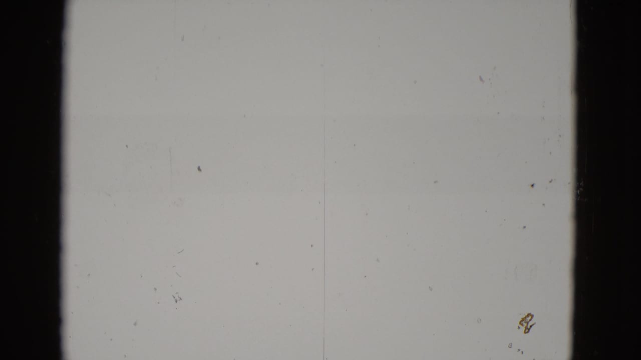 Almost completely blown-out 8mm frame from what appears to be a 1952 Utah desert shoot; only grain, dust specks, and a faint mark at lower-right are discernible.