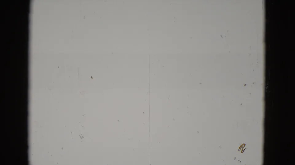 Almost completely blown-out 8mm frame from what appears to be a 1952 Utah desert shoot; only grain, dust specks, and a faint mark at lower-right are discernible.