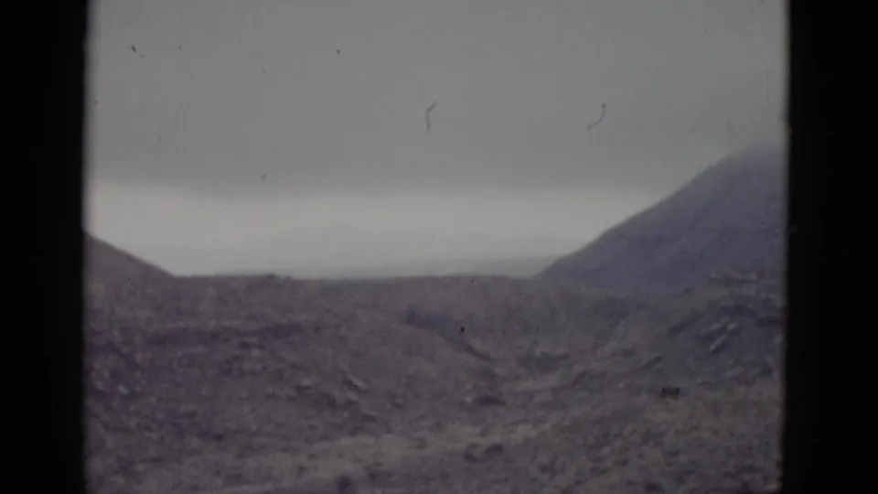 A rounded desert butte in arid terrain consistent with Utah, with film scratches visible in frame, shot on 8mm circa 1952.