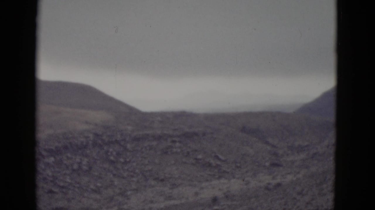 Arid Utah desert landscape with rolling brown hills and overcast sky, filmed on 8mm during a cross-country road trip circa 1952.