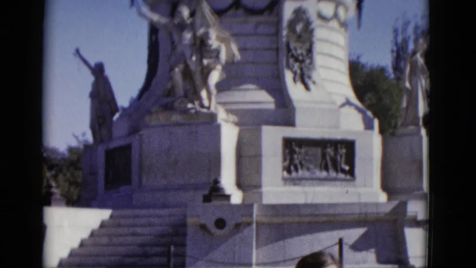 Close-up of a white stone commemorative monument in Utah, 1952, showing heroic sculptural figures with a raised arm and a bas-relief panel against blue sky.