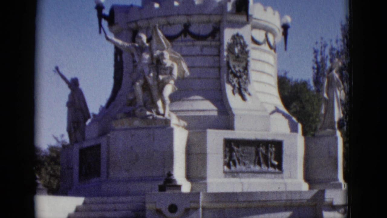 White stone monument with sculptural figures and crenellated tower, seen from below, 8mm 1952.