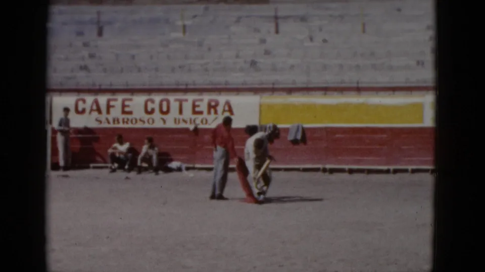 Practice figure in white near the sandy arena floor, circa 1952 Baja California; 'Cafe Cotera' advertisement painted on arena barrier wall.