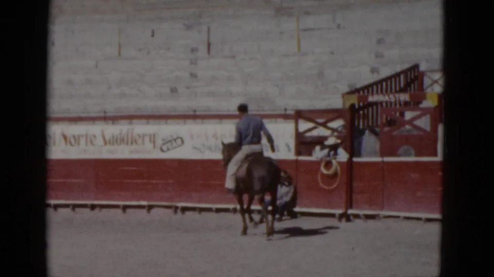 Amateur 8mm color film, circa 1952, Baja California, Mexico: rider on brown horse in sunlit arena with Del Norte Saddlery signage on barrier wall.