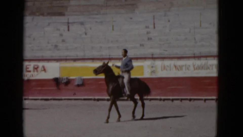 8mm home movie, circa 1952, Baja California, Mexico: rider on brown horse with clearly legible arena advertising on painted concrete barrier wall.